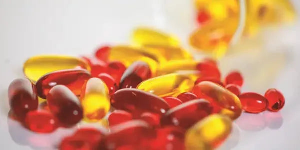 Omega-3 softgel capsules and red supplement pills on a white surface for eye health