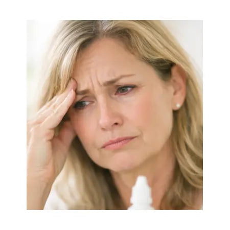Woman with dry, irritated eyes holding eye drops, looking concerned