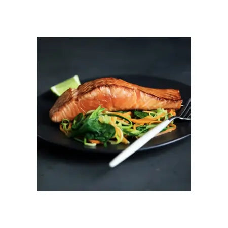 Grilled salmon fillet with sautéed vegetables and lime on black plate