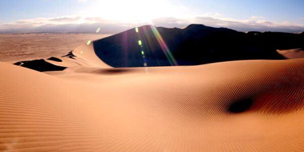 Bright sunlight over dry, rippled sand dunes in a desert, symbolizing dry eye symptoms