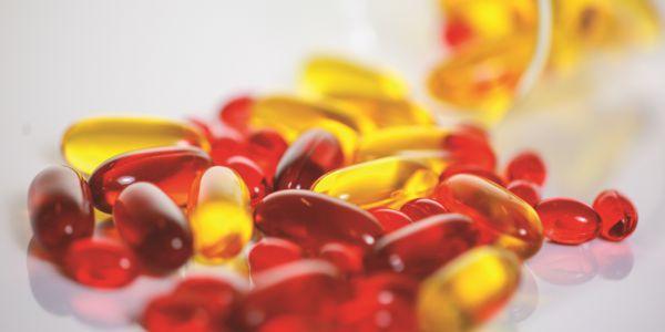 Close-up of red and yellow gel capsules supplements on a white surface