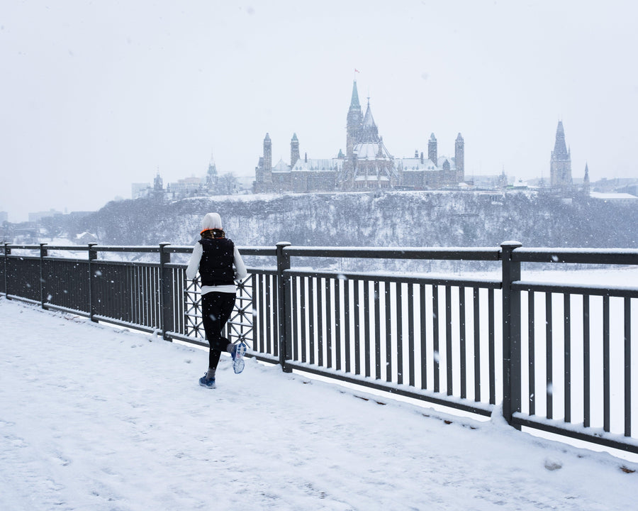 Runner on snowy path with Ottawa skyline and Parliament buildings in winter