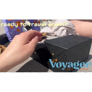 Hand reaching for black mini case with text 'Voyager' and 'ready to travel again?'